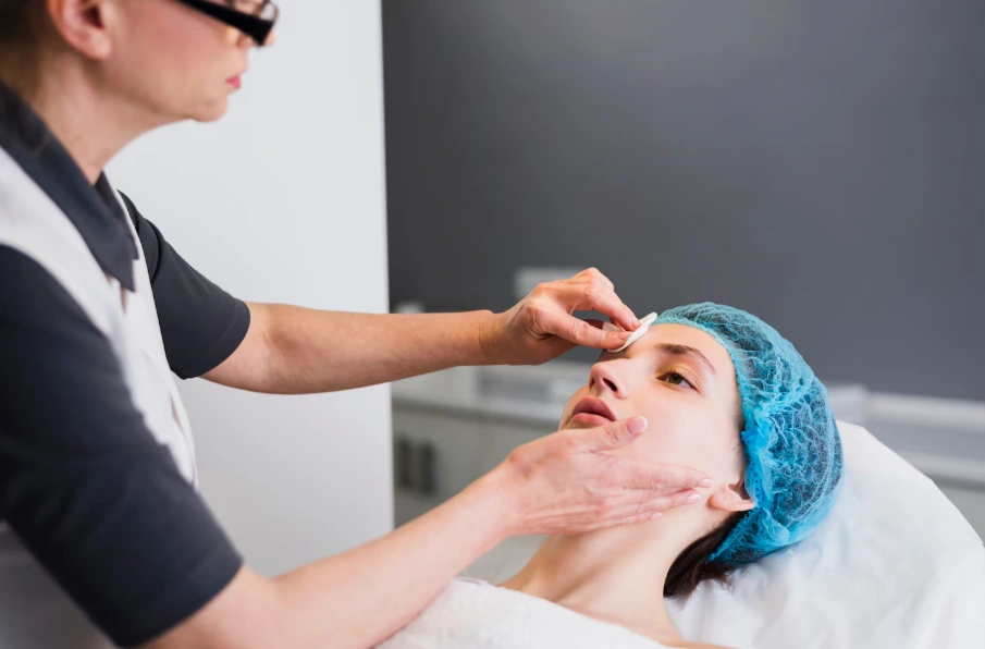 Skincare specialist prepping a client's skin before a facial treatment at Glow Up Studio
