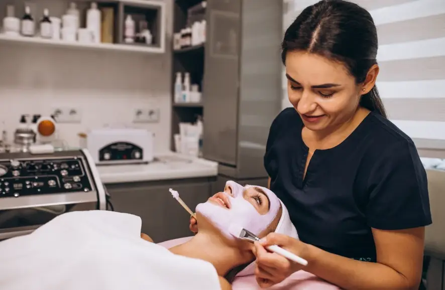 Esthetician at Glow Up Studio applying a facial mask before comparing microdermabrasion vs microneedling vs dermaplaning treatments