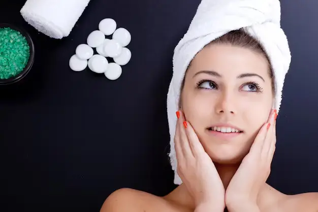 Smiling woman with a towel wrap relaxing after receiving one of the best facials in dallas at a luxury spa
